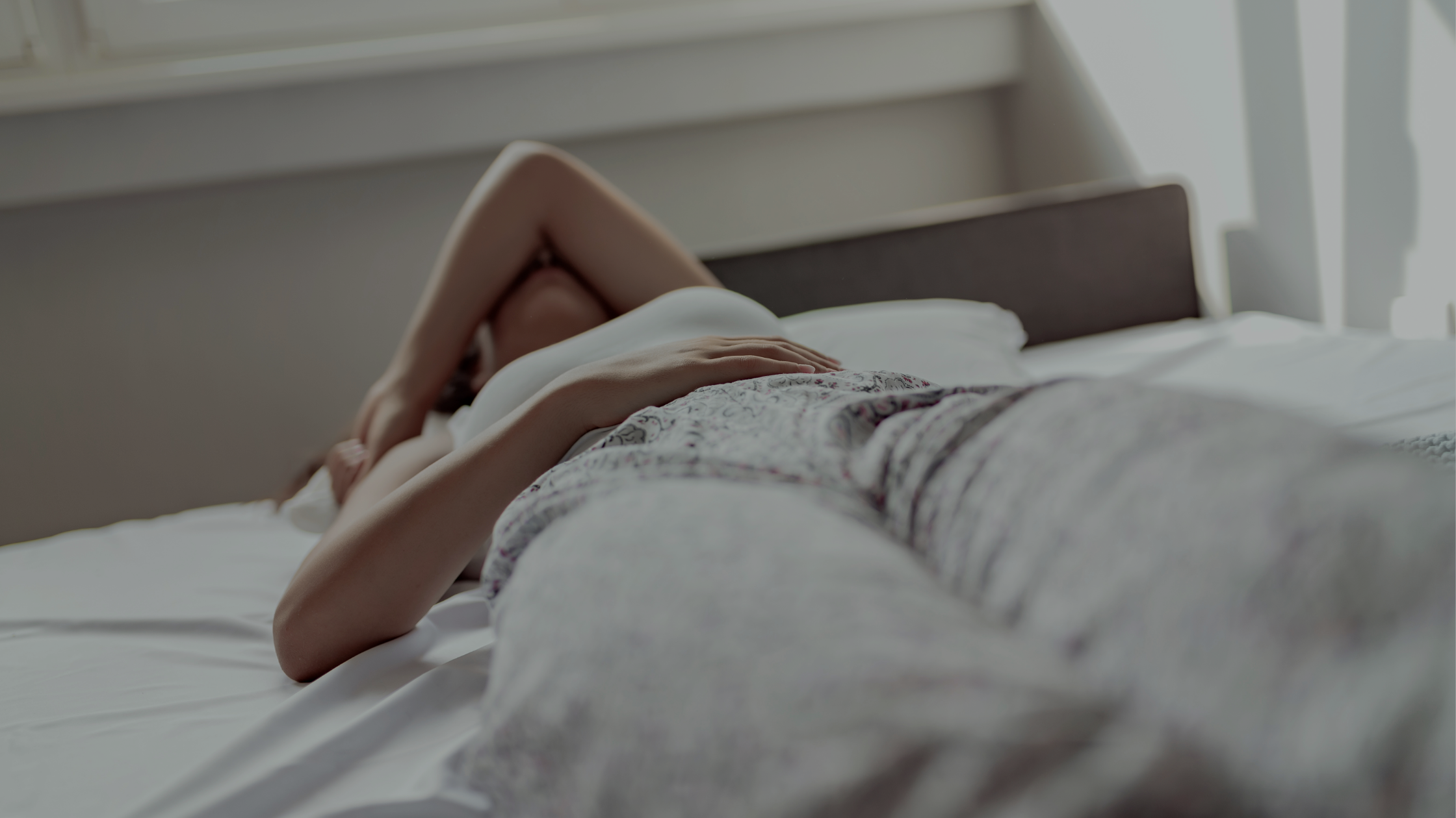 A woman laying in bed, struggling to get up in the morning.